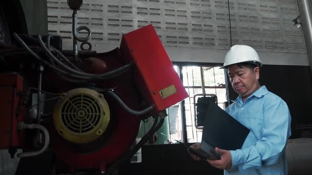 An asian senior engineer or mechanic using industrial machine controller in factory