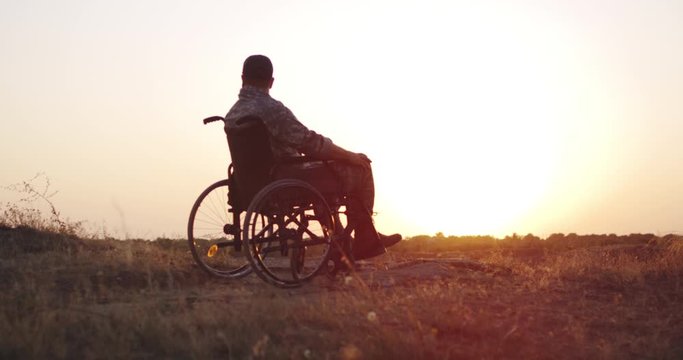 Soldier sitting in a wheelchair on a meadow