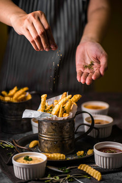 The chef sprinkles french fried seasoned oregano.Kontsept delicious food and healthy food. On a black background for design or lettering text. in lighting studio