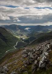 View of the valley of Glen Etive from the Stob Dubh peak, summit of the Buachaille Etive Beag, with Loch Etive in the background and rocks in the foreground. Highlands of Scotland. Munros. Hiking. Hil