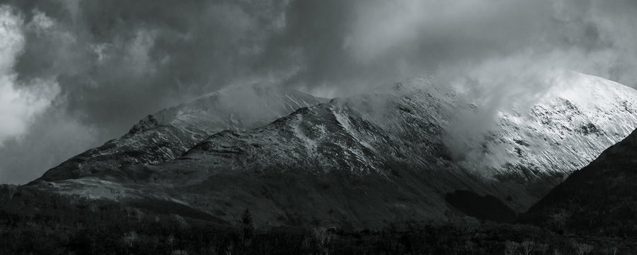 Black and White landscape. View towards Ballachulish across Loch Linnhe from Ardgour. Highlands of Scotland, with snow on the mountains and low hanging clouds with spots of sun breaking through. UK