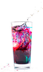 Color that drips into a glass of water on a white background