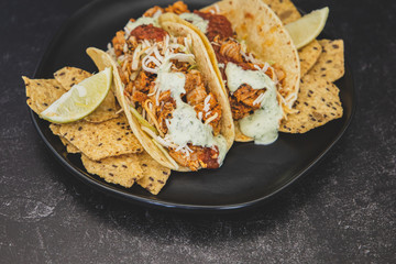 Mexican fresh chicken tacos with cabbage, cheese and cilantro cream sauce in a flour tortilla with multigrain corn tortilla chips