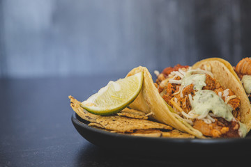 Mexican fresh chicken tacos with cabbage, cheese and cilantro cream sauce in a flour tortilla with multigrain corn tortilla chips