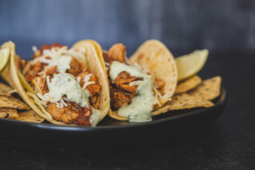 Mexican fresh chicken tacos with cabbage, cheese and cilantro cream sauce in a flour tortilla with multigrain corn tortilla chips