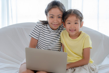 Happy Asian little girl using laptop in living room