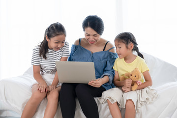 Fototapeta premium Mother and two daughters are using laptops for learning. Happy families