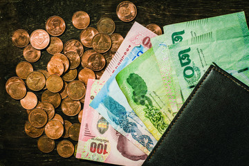 Thai coins and banknotes folded into pockets on old wooden floors.