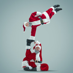 Happy Christmas Santa Claus on grey studio background. Caucasian male model in traditional holiday's costume. Concept of holidays, new year's, winter mood, gifts. Jumping, making tricks. Copyspace.