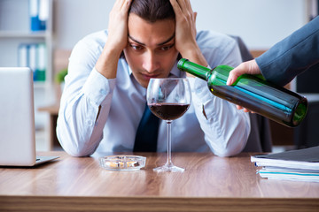 Male employee drinking alcohol and smoking cigarettes at workpla