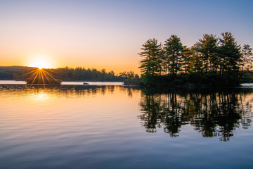 Obraz premium Peaceful sunrise over the lake at Harriman park, featuring sun raising over the mountains on the background