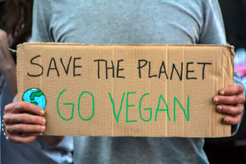 Activist with " Save the planet, Go Vegan" placard at climate change prostest