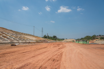 Fototapeta na wymiar Unfinished road, perspective view of wide and flat red mud road space
