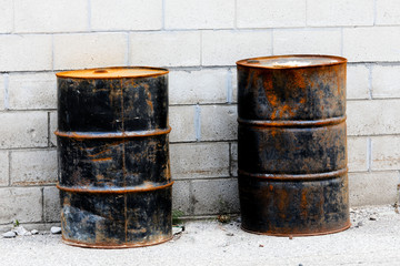 Old steel oil drums by the cement block wall of an industrial site