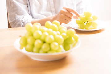 ぶどう（シャインマスカット）を食べる女性