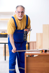 Old male carpenter working in workshop