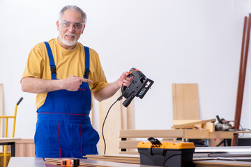 Old male carpenter working in workshop