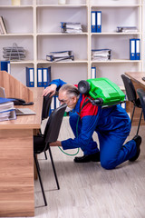 Old professional contractor doing pest control in the office