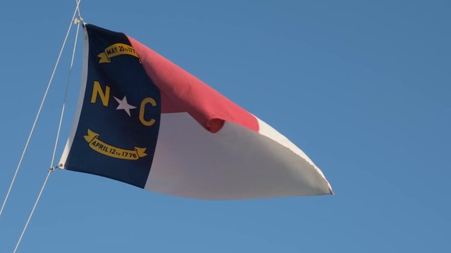 North Carolina State Flag waves proudly in the wind against a blue sky. slow motion footage