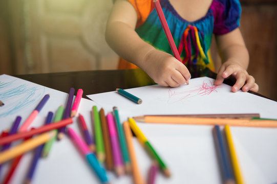 little girl learn to draw and paint with various pencil colour and white paper on wooden desk, family relationship concept, home school, holding pencil colour