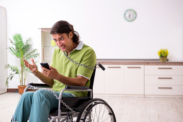 Young male invalid in wheel-chair suffering at home