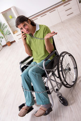 Young male invalid in wheel-chair suffering at home