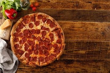 Pepperoni pizza on a wooden table. Still life with ingredients. Top view. Copy space.