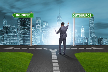 Businessman at crossroads deciding between outsourcing and inhou