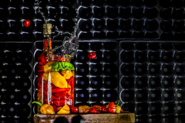 Fototapeta na wymiar Peppers in motion ,colorful composition of peppers, chili sauce and preserved preserves in bottle and pot.