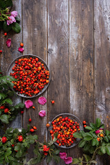 Dog rose berries and leaves on a wooden table. harvest rose hips