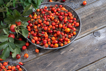 Dog rose berries and leaves on a wooden table. harvest rose hips