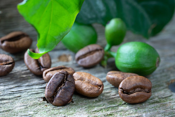 Leaves, berries and beans of coffee on wooden background. Macro. Vertical