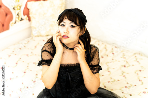 ゴスロリのコスプレをしてベッドに座る女性 Wall Mural Promolink