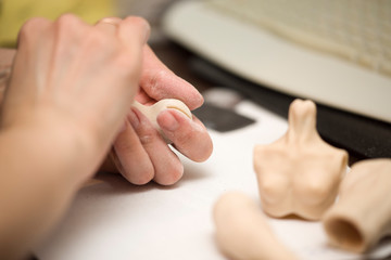Girl hands polishing parts for making dolls from polymeric material.
