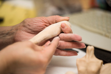 Girl hands polishing parts for making dolls from polymeric material.