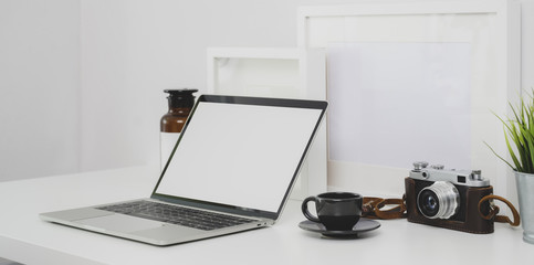 Trendy photographer workplace with blank screen laptop and office supplies