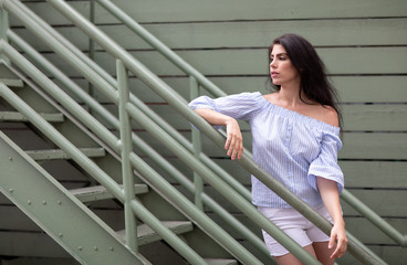 Beautiful young woman next to industrial stairs on the backstreet