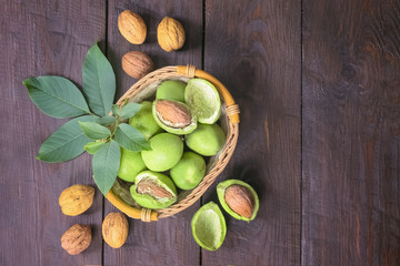 ripe fresh walnuts with leaves and green peel in a wicker basket top view. walnuts on wooden background. copy space. flat lay.