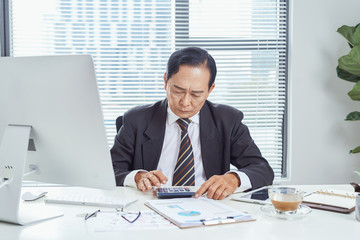 Middle aged Asian businessman feeling stressed and frustrated while working in work station. Business problem concept