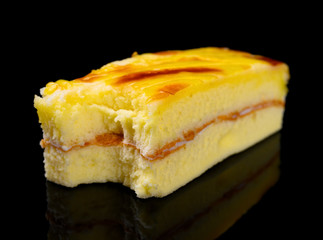 square shape cheese cake with a bite on black background