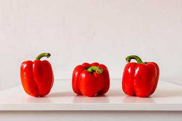 Three red bulgarian pepper on a white table, close up