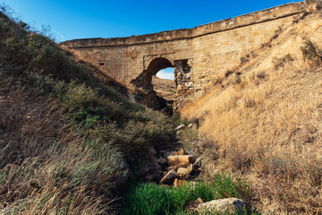 Fototapeta na wymiar Old dilapidated stone bridge over a small mountain river