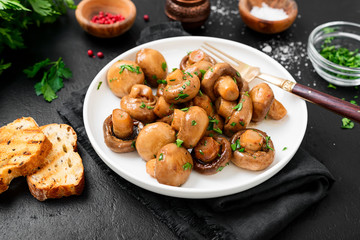 Fried mushrooms with fresh herbs in white plate. 