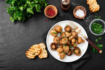 Fried mushrooms with fresh herbs in white plate. Top view.