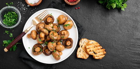 Fried mushrooms with fresh herbs in white plate. Top view.