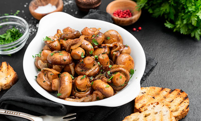 Fried mushrooms with fresh herbs in white plate. 