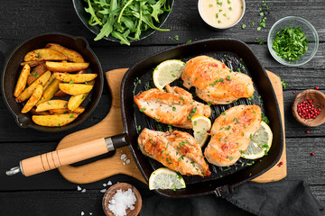 Fresh chicken breast seared in a cast iron skillet with baked potato and arugula salad.