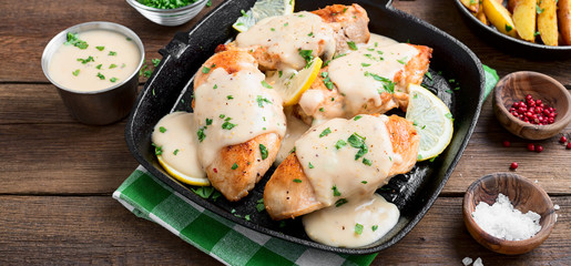 Fresh chicken breast seared in a cast iron skillet with creamy pan sauce.