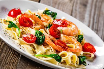 Shrimps with pasta tagliatelle with spinach and tomatoes