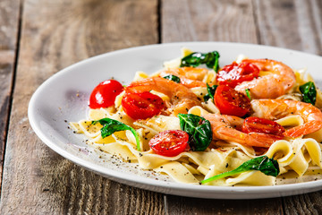 Shrimps with pasta tagliatelle with spinach and tomatoes